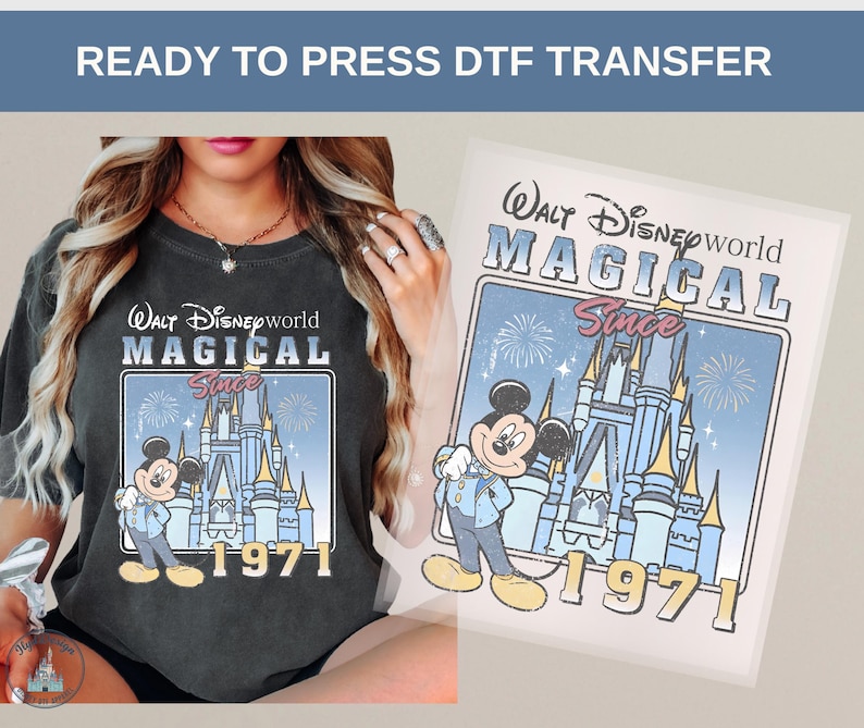 Może przedstawiać: Ciemnoszara koszulka z nadrukiem w stylu retro przedstawiającym Myszka Miki przed zamkiem Kopciuszka, z napisem "Walt Disney World MAGICAL Since 1971." Widoczny jest r&oacute;wnież transfer DTF gotowy do prasowania.