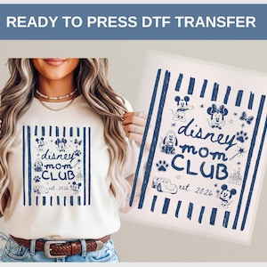 May include: A cream-colored t-shirt and a separate transfer sheet, both featuring a dark blue graphic with vertical stripes and the text "disney mom CLUB est. 2026". The design includes illustrations of Mickey Mouse, Minnie Mouse, Pluto, Lightning McQueen, a castle, a bow, a wand, and paw prints.