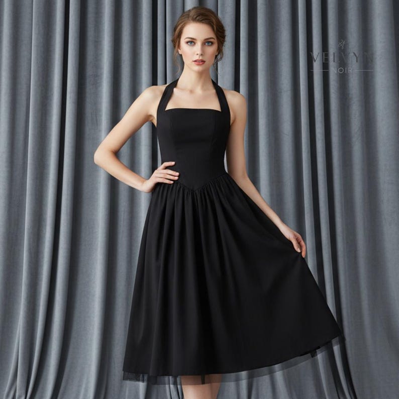 May include: A black halter dress with a square neckline and a flared skirt. The dress has a fitted bodice and a flowing skirt that falls to the mid-calf. The dress is made of a soft fabric and has a sheer hemline. The dress is suitable for formal events.