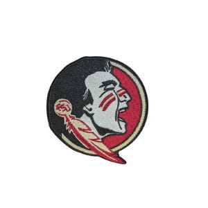 Puede incluir: Parche bordado con un perfil de cabeza de Seminola dentro de un diseño circular. El parche tiene un fondo negro con un borde rojo y crema. La cabeza de Seminola se representa con pintura facial roja y una pluma roja y crema.