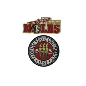 Puede incluir: Dos parches bordados con el logotipo de la Universidad Estatal de Florida. El parche superior dice "NOLES" con una lanza y las palabras "Florida State" arriba. El parche inferior es circular, con las palabras "Florida State University" y el año "1851".