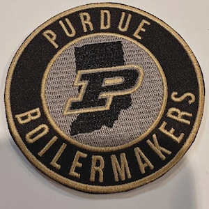May include: Circular patch with the words "PURDUE BOILERMAKERS" in gold lettering. The center features a black outline of Indiana with a gold "P" inside. The patch has a black border with gold stitching.