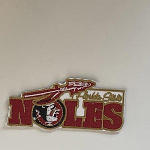 Può includere: Una tazza di ceramica bianca con manico nero e la scritta "But first, coffee" in nero, con un font a mano libera. La tazza è su una superficie bianca.