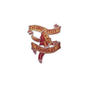 Puede incluir: Parche bordado con el logotipo de los Seminoles de la Florida State. El parche tiene una combinación de colores granate y dorado, con las palabras "FLORIDA STATE" y "SEMINOLES" en cintas doradas. El diseño central es una punta de lanza estilizada.