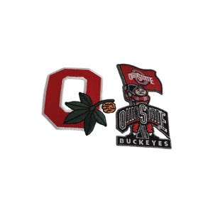 May include: Two embroidered patches featuring Ohio State University logos. One patch is a red "O" with a white border and a green leaf and brown acorn design. The other patch is a mascot holding a flag that says "Ohio State" and the word "Buckeyes".