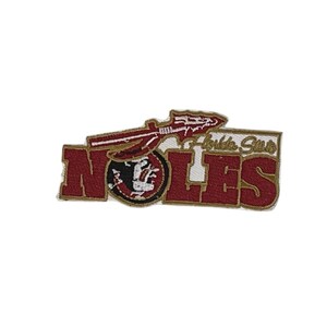 Puede incluir: Parche bordado con la palabra "NOLES" en letras de bloque granate y un borde dorado. El parche incluye una lanza y las palabras "Florida State" en letras doradas, y un logotipo de cabeza de Seminole.