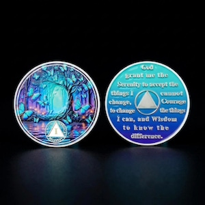 May include: Two round, metallic recovery tokens. One features a tree and butterflies in shades of blue and purple. The other has a teal and blue gradient with the Serenity Prayer and a triangle symbol. The text reads "RECOVER".