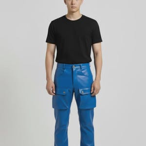 May include: A person wearing a black crew neck t-shirt and bright blue pants with two large pockets on each leg. The pants are made of a shiny material. The person is wearing black shoes.