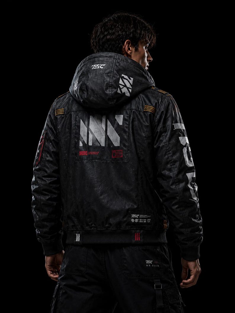 May include: A black hooded jacket featuring white and red graphic prints on the back and sleeves. The back displays large white text and geometric patterns, while the hood and sleeves include additional white branding and orange accents.