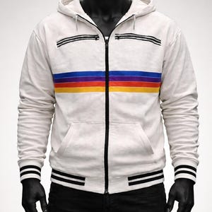 Puede incluir: Sudadera blanca con cremallera y diseño de rayas horizontales de colores en el pecho. La sudadera tiene una cremallera negra, rayas negras en las mangas y la cintura, y una capucha. Se muestra en un maniquí.