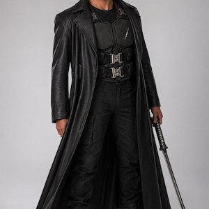 Puede incluir: Una persona con un abrigo largo de cuero negro, chaleco t&aacute;ctico y pantalones cargo, sosteniendo una katana. El atuendo incluye una camiseta negra y botas de combate. La imagen est&aacute; sobre un fondo liso.