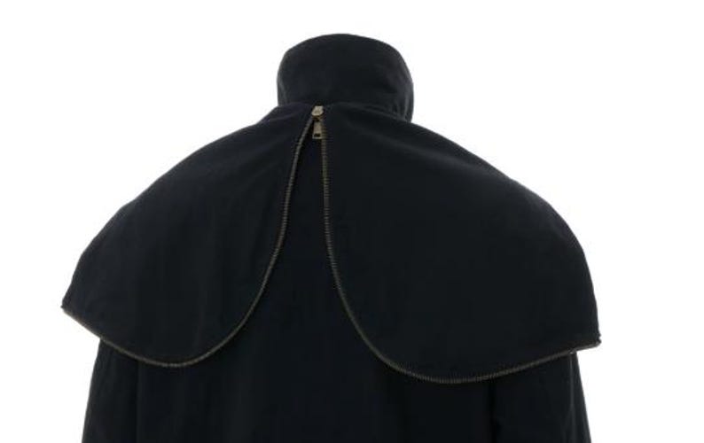 May include: A black coat featuring a detachable cape-style collar that wraps around the shoulders. The collar is secured with a prominent metal zipper that runs along the curved edge, meeting at the center back near the high neckline.