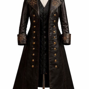 Puede incluir: Abrigo largo marrón oscuro con botones dorados y costuras decorativas. El abrigo presenta un diseño cruzado, un cuello con muescas y un chaleco a juego debajo. Los puños y el cuello tienen diseños de rosa de los vientos bordados. El abrigo se exhibe en un maniquí.