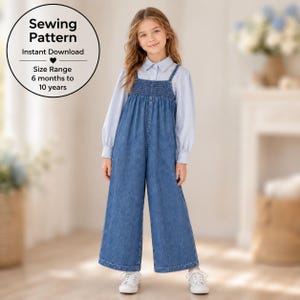 May include: A sewing pattern for a blue denim jumpsuit with a smocked bodice and wide legs, worn over a light blue long-sleeved collared shirt. The text reads: Sewing Pattern, Instant Download, Size Range 6 months to 10 years.