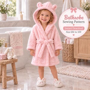 Può includere: Un morbido accappatoio in peluche rosa chiaro con un cappuccio dotato di piccole orecchie arrotondate. L'accappatoio presenta maniche lunghe, una cintura in vita e una consistenza soffice. Un grafico circolare mostra il testo Bathrobe Sewing Pattern, Instant Download, Size 6M to 10Y.