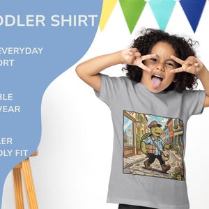 K&ouml;nnte beinhalten: Graues Kinder-T-Shirt mit einem Cartoon-Schildkr&ouml;ten-Motiv, das eine Stra&szlig;e entlangl&auml;uft. Auf dem Shirt stehen die Worte "TODDLER SHIRT", "SOFT EVERYDAY COMFORT", "DURABLE PLAYWEAR" und "TODDLER FRIENDLY FIT".