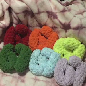 Może przedstawiać: Sześć ręcznie robionych gumek do włosów w różnych kolorach: czerwonym, pomarańczowym, zielonym, jasnoniebieskim, limonkowym i lawendowym. Gumki wykonane są z miękkiego, teksturowanego materiału i ułożone na wzorzystym tle.