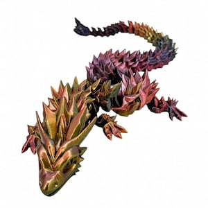 May include: A detailed, articulated lizard sculpture with a metallic finish. The body transitions from gold to red, purple, and blue, with sharp, spiky scales. The lizard has detailed feet and a long, curved tail, perfect for home decor.