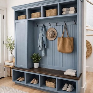 May include: A blue entryway storage unit with a bench, shoe cubbies, and upper shelves. Wicker baskets, a denim jacket, a hat, and a tote bag hang from hooks. A rug and shoes are in the foreground.