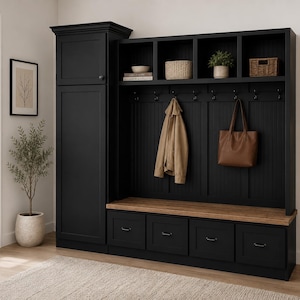 May include: A black entryway storage unit with a bench, drawers, and coat hooks. The unit has a wooden bench top and a tall cabinet on the left. A tan jacket and brown tote bag hang from the hooks. A small plant and decorative baskets sit on the shelves.