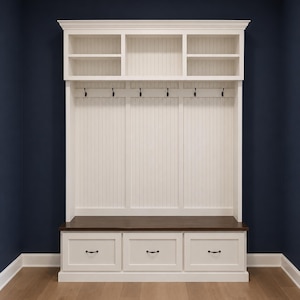 May include: A white wooden entryway organizer with a dark brown bench seat and three drawers. Above the bench are six coat hooks and a shelf with three compartments. The organizer is set against a dark blue wall.