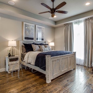 May include: A whitewashed wood bed frame with a white, blue, and gray patterned comforter. The bed is in a bedroom with white walls, wood floors, and a large window with white curtains.