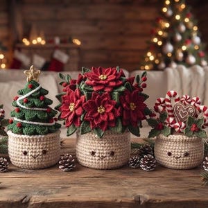 Op de afbeelding: Een set van vijf gehaakte kerstdecoraties in beige potjes met geborduurde gezichtjes. De figuren bestaan uit een kerstman, een groene kerstboom, een rode kerstster, zuurstokken met een hartje en een klein rendier.