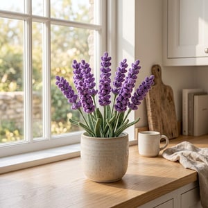 Può includere: Una pianta di lavanda all'uncinetto con vivaci spighe di fiori viola e steli verdi testurizzati, inserita in un vaso cilindrico in ceramica maculata. La pianta presenta molteplici steli di altezze variabili con una lavorazione dettagliata.