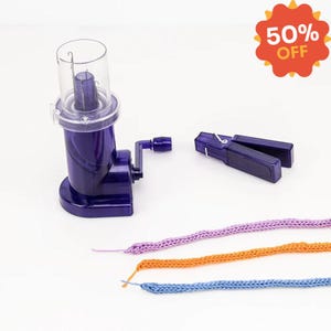 May include: A purple yarn winder with a clear plastic top, a yarn swift, and three colorful yarn samples. The yarn samples are purple, orange, and blue. A 50% off sticker is in the top right corner.