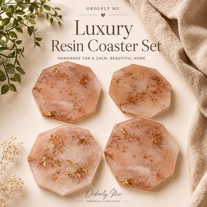May include: A set of four hexagonal resin coasters. The coasters are a light pink color with gold leaf accents. The text "Luxury Resin Coaster Set" is displayed above the coasters. The coasters are handmade.