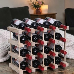 May include: A wooden wine rack holding multiple bottles of red wine. The rack is made of light-colored wood and has a grid-like structure. The wine bottles are dark with red caps, and the labels are visible.