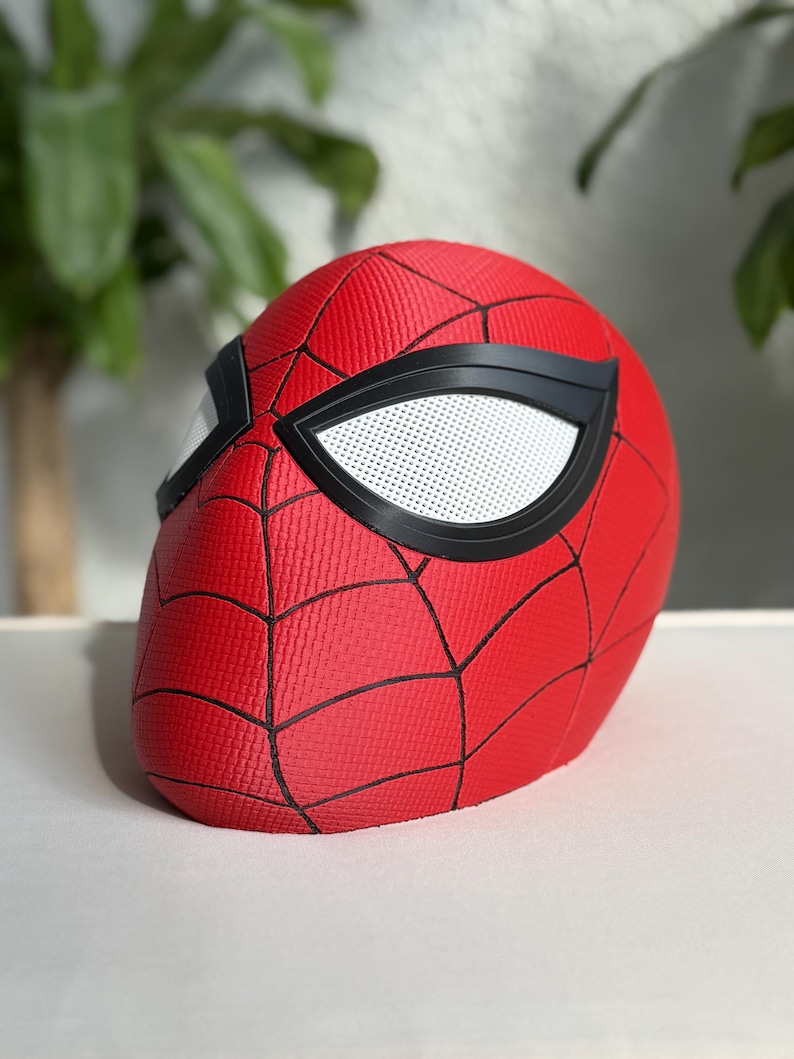 May include: A red Spider-Man mask with black web lines and black eye frames. The eye lenses are white with small perforations. The mask is made of a textured material.