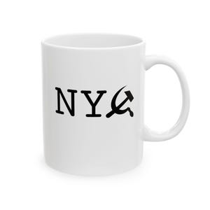 May include: White ceramic mug with a black "NYC" design, where the "C" is replaced with a hammer and sickle symbol. The mug has a curved handle and a cylindrical shape.