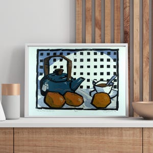 Puede incluir: Una impresión enmarcada que presenta una naturaleza muerta de una tetera azul, una taza de té y tres bollos marrones. El fondo tiene un patrón de cuadros azules y blancos. La obra de arte se exhibe en un estante blanco.