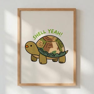May include: A framed art print featuring a cartoon turtle with a green and brown shell. The text "SHELL YEAH!" is written above the turtle in green letters. The artwork is set against a cream-colored background.
