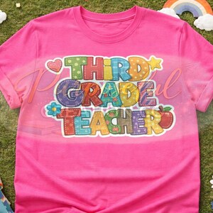 Può includere: Una maglietta rosa acceso con la scritta "THIRD GRADE TEACHER" in lettere colorate in stile patchwork. Il design include cuori, stelle, fiori e una mela. La maglietta è esposta su una superficie erbosa con decorazioni a tema scolastico.
