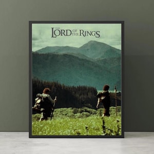 Puede incluir: Póster enmarcado con el título "The Lord of the Rings" en la parte superior. La imagen muestra dos figuras caminando por un campo de hierba hacia montañas y un bosque. El póster está en un marco negro.
