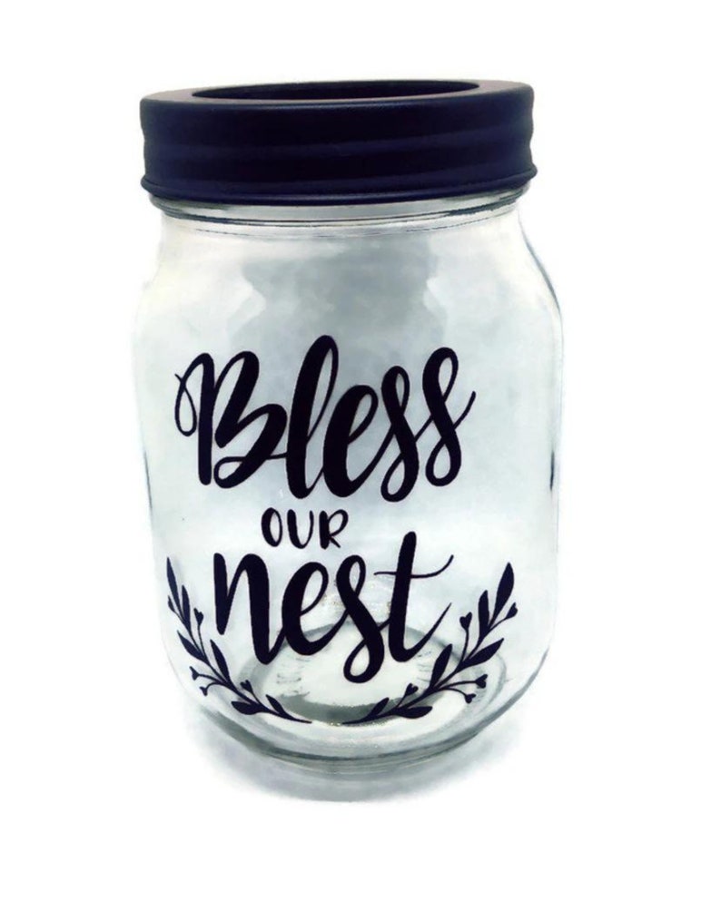 May include: A clear glass jar with a black lid and a black vinyl decal that says "Bless our nest".