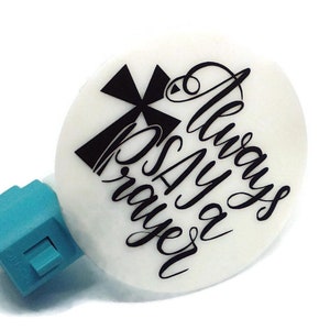 May include: A white night light with a black cross and the text "Always Say a Prayer" in a decorative font.