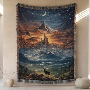 May include: A woven tapestry featuring a fantasy landscape with a castle, mountains, and a deer. The artwork depicts a night sky with a crescent moon and stars. The tapestry has a fringed edge and is displayed on a wall.