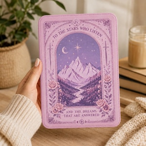 Op de afbeelding: Een lila tablet hoesje met een illustratie van een berglandschap onder een sterrenhemel, met de tekst "TO THE STARS WHO LISTEN" en "AND THE DREAMS THAT ARE ANSWERED". Het ontwerp bevat bloemen- en zwaardmotieven.