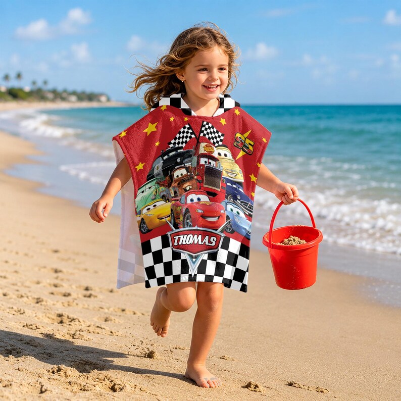 May include: A red hooded poncho towel featuring a graphic print of various race cars from the movie Cars, including Lightning McQueen, with yellow stars, checkered flags, and a black and white checkered border at the bottom with the name Thomas.