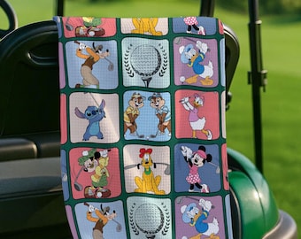 Könnte beinhalten: Ein Golfhandtuch mit einem sich wiederholenden Muster von Disney-Figuren, die Golf spielen. Das Design umfasst Charaktere wie Goofy, Donald Duck und Minnie Mouse, vor dem Hintergrund farbiger Quadrate. Das Handtuch ist grün und weiß.