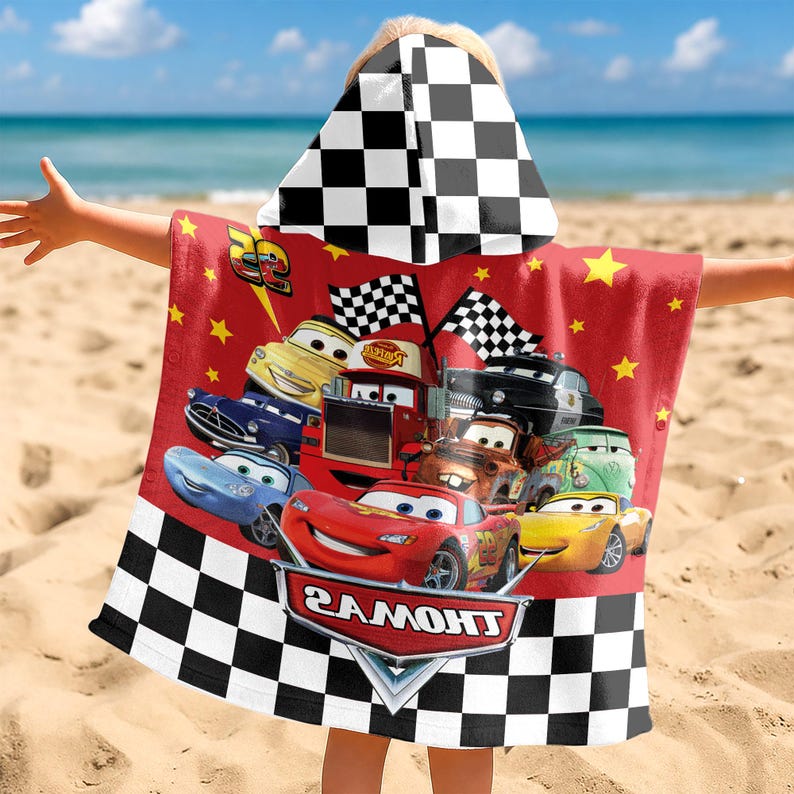 May include: A red hooded towel featuring a black and white checkered pattern on the hood and bottom hem. The center displays various cartoon race cars, including a red car with the number 95, and a logo with the text THOMAS in white letters.