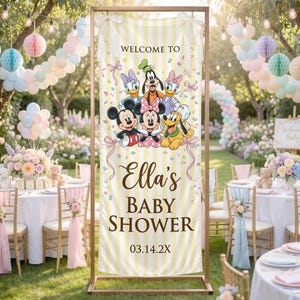 May include: A vertical banner with yellow and white vertical stripes featuring Disney characters including Mickey Mouse, Minnie Mouse, Goofy, Donald Duck, Daisy Duck, and Pluto. The text reads WELCOME TO Ella's BABY SHOWER 03.14.2X with ribbons.