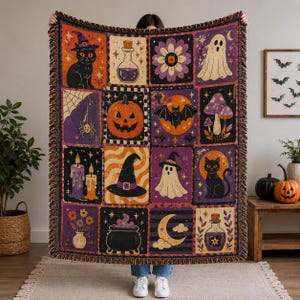 May include: A woven throw blanket featuring a grid of Halloween-themed illustrations including a black cat, a jack-o'-lantern, a ghost, a witch hat, a cauldron, mushrooms, bats, and potion bottles in a color palette of orange, purple, and black.