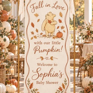 Pode incluir: Uma faixa vertical de tecido cor de creme suspensa num suporte de metal dourado com fitas bege. A faixa apresenta um urso, folhas de outono e uma abóbora, com o texto: Fall in Love with our little Pumpkin! Welcome to Sophia's Baby Shower.