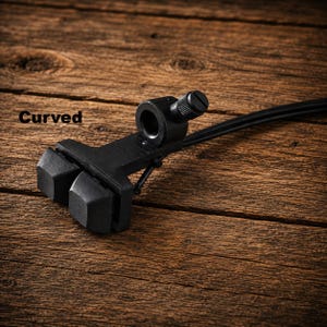 Peut inclure: Un ensemble de patins de frein de vélo noir comprenant deux patins en caoutchouc rectangulaires montés sur un support métallique avec un point de fixation cylindrique et une vis de réglage. Le mot Curved est imprimé en noir à gauche.