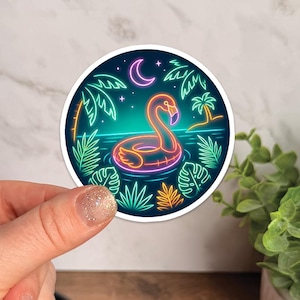 May include: A round sticker featuring a neon flamingo float in water, surrounded by palm trees and tropical plants. The design includes a crescent moon and stars against a dark blue background. The sticker has a white border.