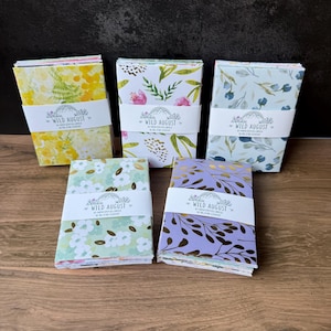 May include: Five stacks of stationery cards and envelopes, each wrapped in a white paper band labeled Wild August 30 mini envelopes 30 blank cards. The patterns include yellow floral, green and pink botanical, blue floral, light green floral, and purple with gold leaves.